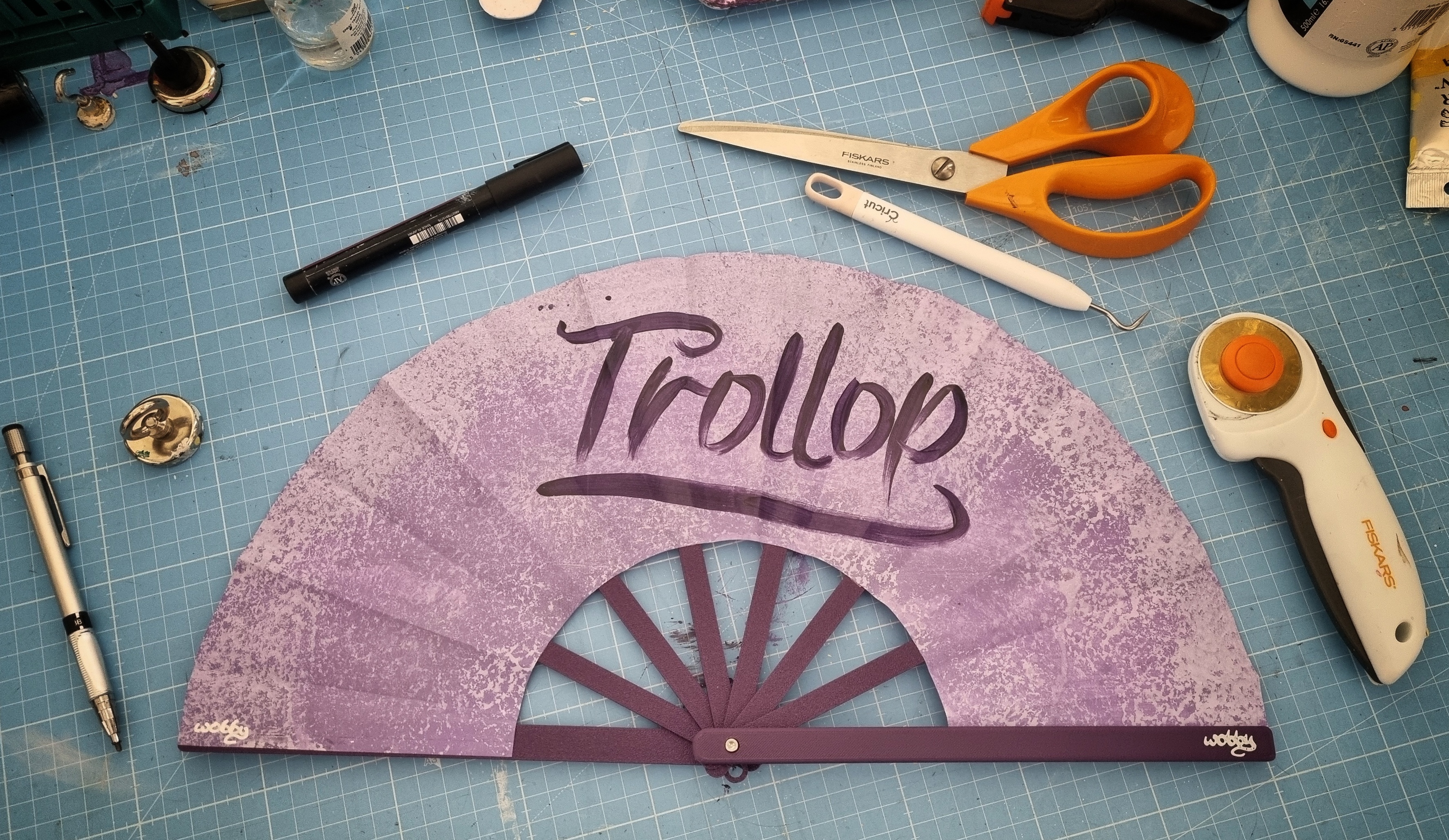 Purple painted fan with 'Trollop' painted on a dark purple frame